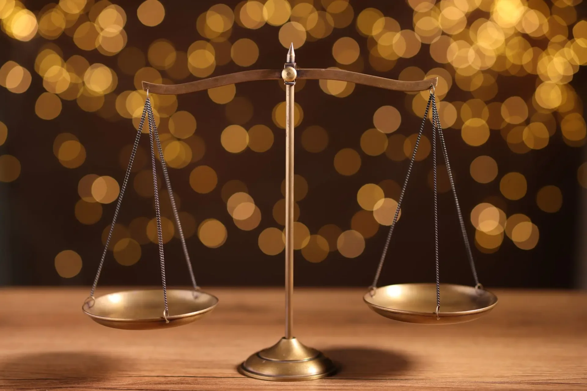 Brass balance scales with golden bokeh background